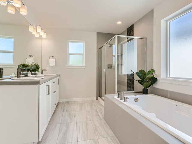 full bath with a sink, double vanity, a stall shower, and a garden tub