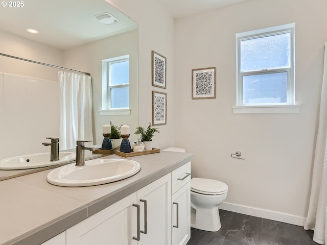 full bath with baseboards, vanity, toilet, and a healthy amount of sunlight