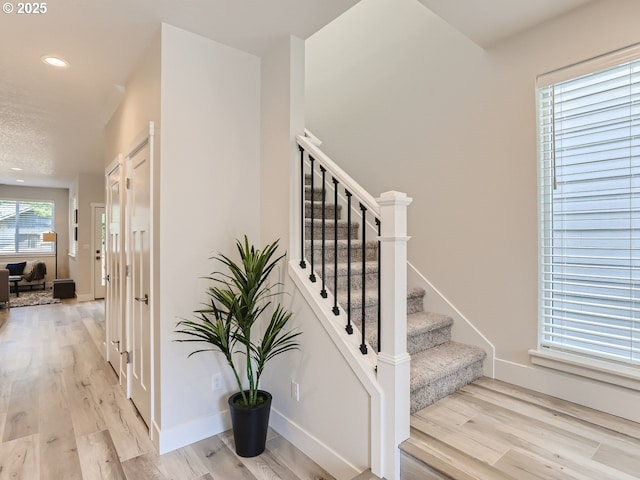 stairway featuring recessed lighting, wood finished floors, and baseboards