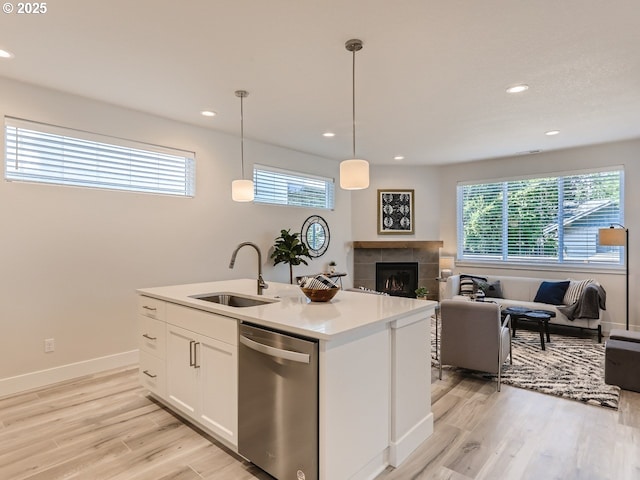 kitchen with sink, a center island with sink, dishwasher, pendant lighting, and white cabinets