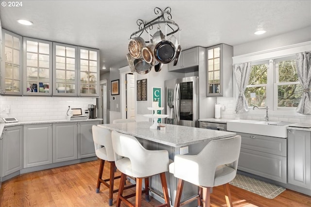 kitchen featuring a breakfast bar, gray cabinets, light wood finished floors, and refrigerator with glass door