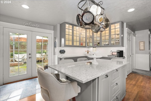 kitchen with a textured ceiling, dark wood-style flooring, a kitchen bar, and gray cabinets