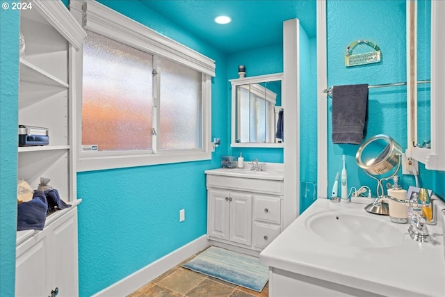 bathroom with a textured wall, vanity, and baseboards