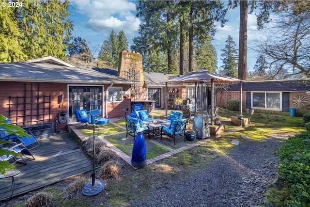 back of house with a chimney, an outdoor living space, and a wooden deck