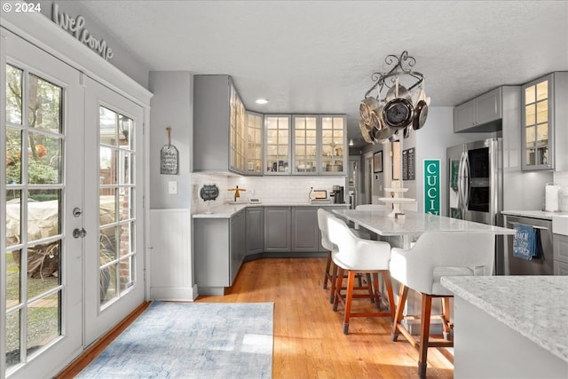 kitchen with light wood-style floors, gray cabinets, a healthy amount of sunlight, and decorative backsplash