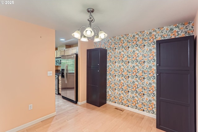 10793 SW Canterbury Ln Unit 101, Portland, OR 97224 - empty room with wallpapered walls, an accent wall, a chandelier, and light wood finished floors