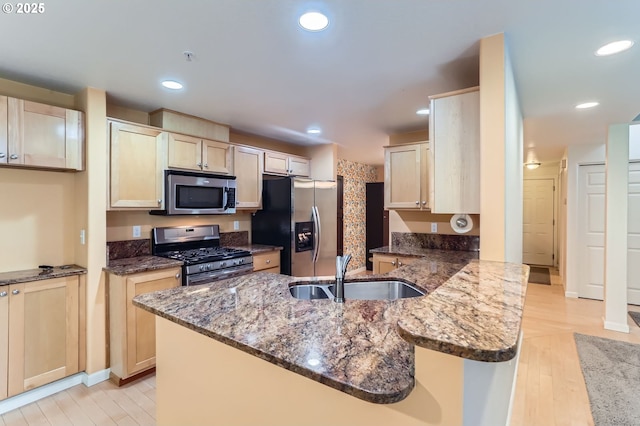 10793 SW Canterbury Ln Unit 101, Portland, OR 97224 - kitchen with stainless steel appliances, a peninsula, dark stone countertops, light wood-type flooring, and recessed lighting