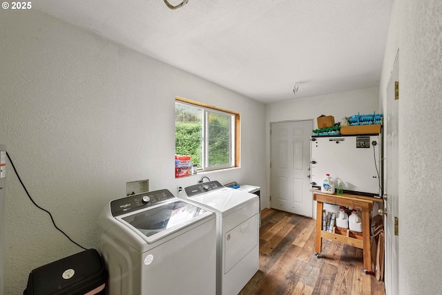 washroom featuring independent washer and dryer, laundry area, a textured wall, and wood finished floors