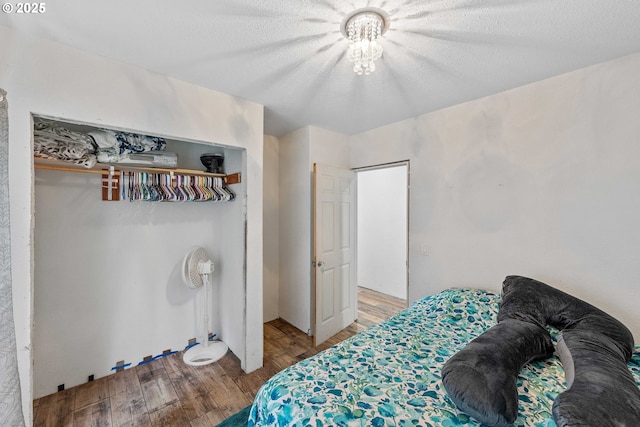 bedroom with a textured ceiling, wood finished floors, and a closet