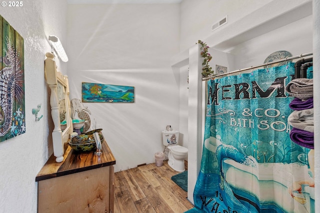 bathroom with visible vents, curtained shower, wood finished floors, vanity, and toilet