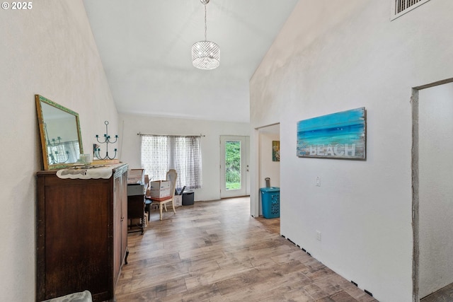 hall with visible vents, wood finished floors, and high vaulted ceiling