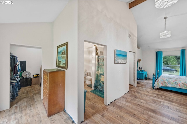 interior space with light wood finished floors, high vaulted ceiling, ensuite bathroom, beamed ceiling, and visible vents