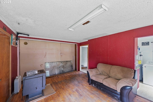 living room featuring a textured ceiling, washer / dryer, wood finished floors, and a wood stove