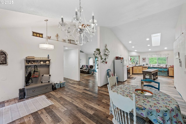 dining room with light wood-style floors, high vaulted ceiling, a chandelier, and a skylight