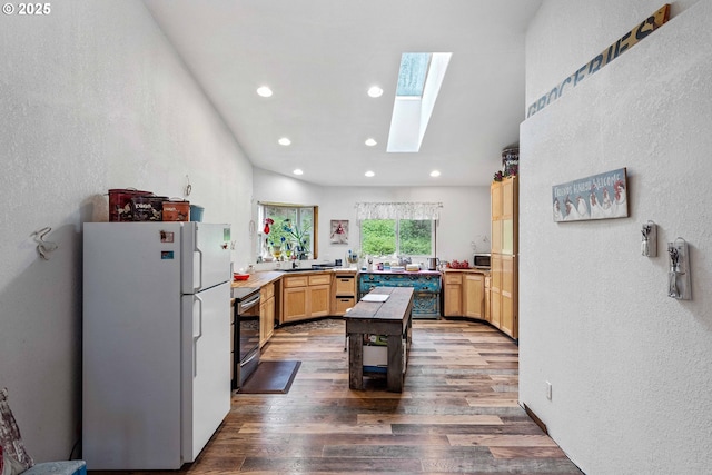 kitchen featuring freestanding refrigerator, a textured wall, wood finished floors, and stainless steel electric stove