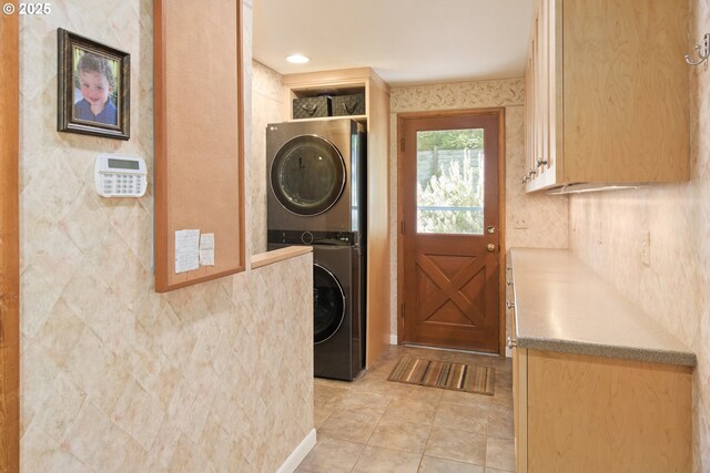 clothes washing area featuring stacked washer and dryer, laundry area, and light tile patterned floors