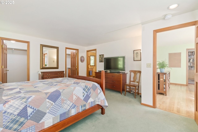 bedroom featuring baseboards, a spacious closet, and light carpet