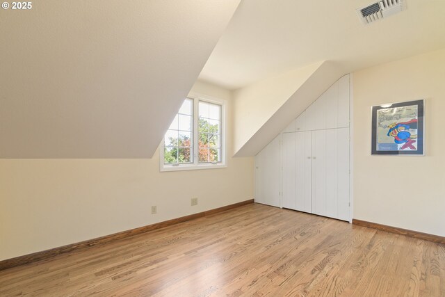 bonus room featuring baseboards, visible vents, lofted ceiling, and light wood-type flooring