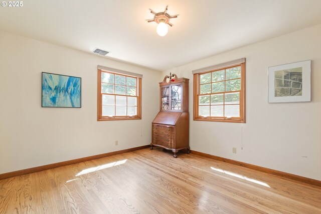 unfurnished room featuring light wood-style floors, baseboards, and a wealth of natural light
