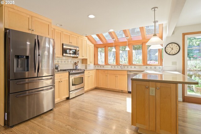 kitchen with light wood finished floors, light brown cabinets, stainless steel appliances, decorative backsplash, and a skylight