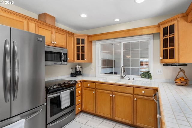 kitchen with stainless steel appliances, sink, tile countertops, and light tile patterned floors