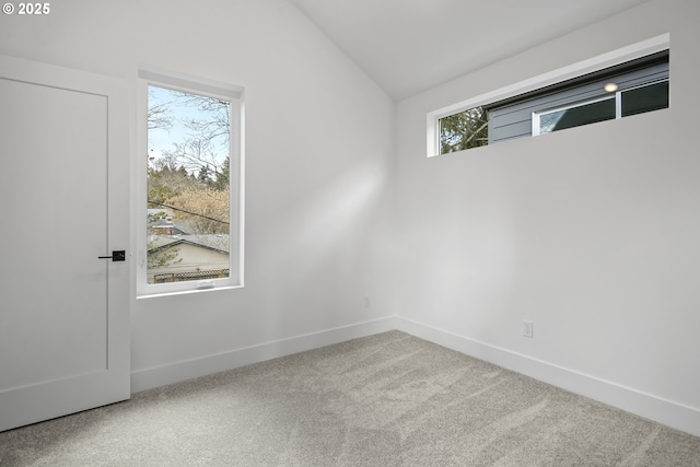 carpeted empty room featuring lofted ceiling