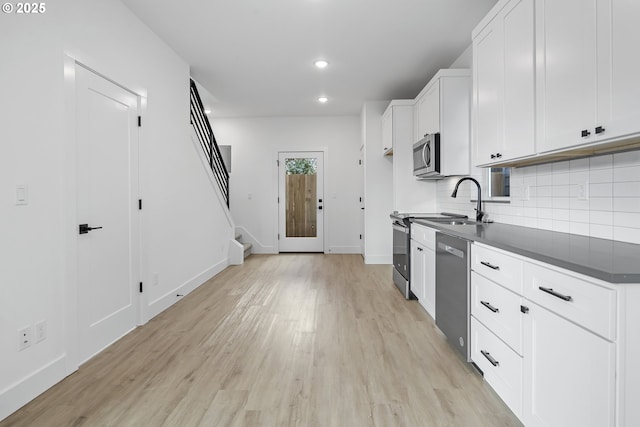 kitchen featuring stainless steel appliances, white cabinetry, tasteful backsplash, and light hardwood / wood-style flooring