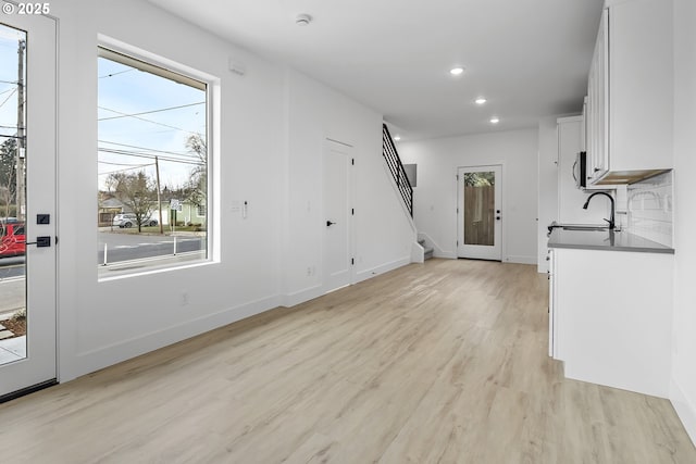 unfurnished living room with sink and light hardwood / wood-style floors