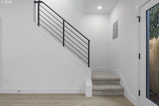 staircase with hardwood / wood-style floors and electric panel