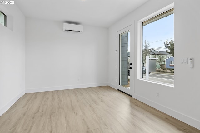 spare room featuring a wall mounted AC and light hardwood / wood-style flooring