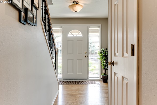 entrance foyer with a wealth of natural light, wood finished floors, and stairway