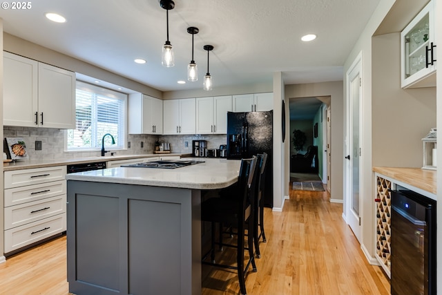 kitchen with light wood finished floors, wine cooler, white cabinetry, and tasteful backsplash