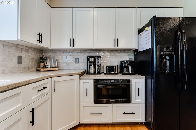 kitchen featuring light countertops, white cabinets, backsplash, and black appliances