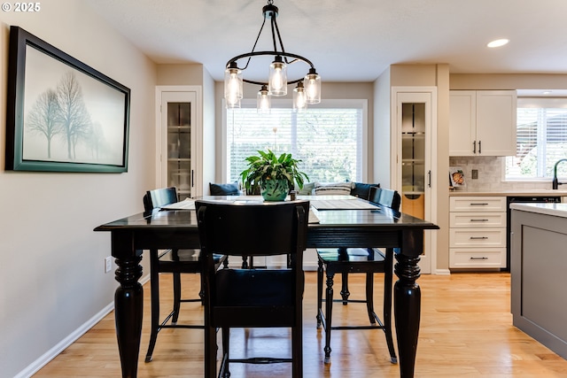 dining space featuring light wood-style floors, recessed lighting, baseboards, and an inviting chandelier