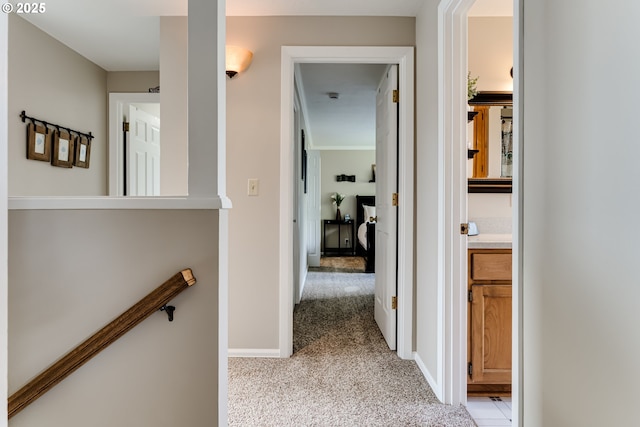 corridor with baseboards and light colored carpet