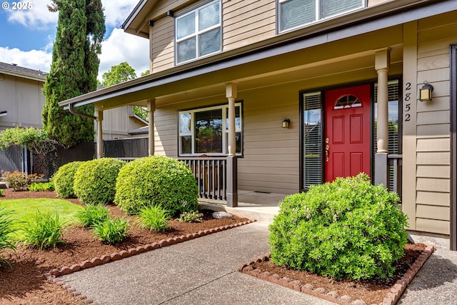 doorway to property with a porch and fence