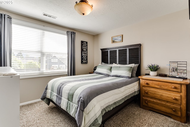 carpeted bedroom with baseboards, a textured ceiling, and visible vents