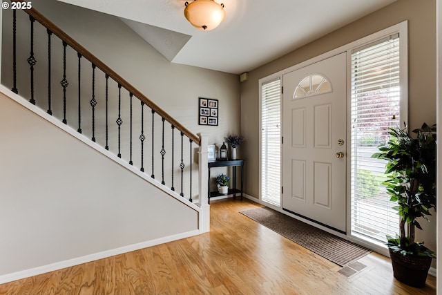 foyer featuring stairs, baseboards, and wood finished floors