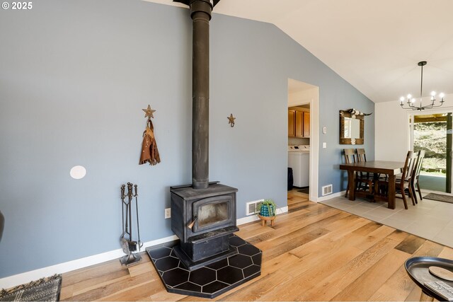 8095 SW High Cone Dr, Terrebonne, OR 97760 - living area featuring a wood stove, a chandelier, vaulted ceiling, wood finished floors, and washer / dryer