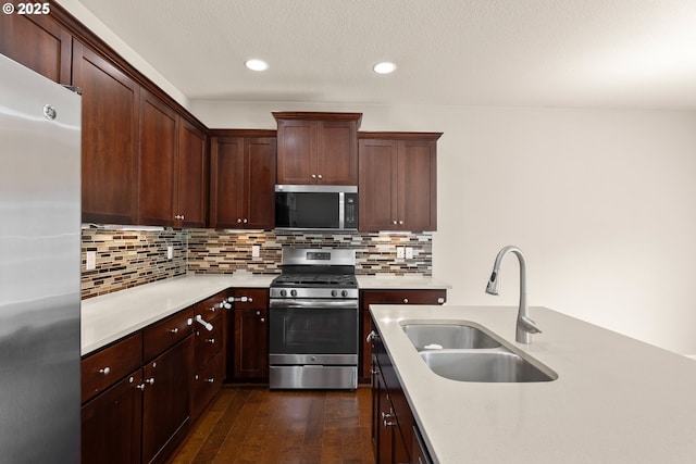 kitchen featuring stainless steel appliances, light countertops, a sink, dark wood-style floors, and recessed lighting