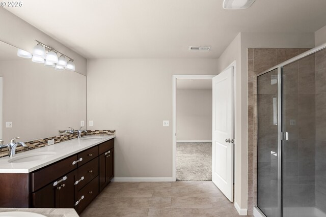 bathroom with a shower stall, double vanity, baseboards, and tile patterned flooring