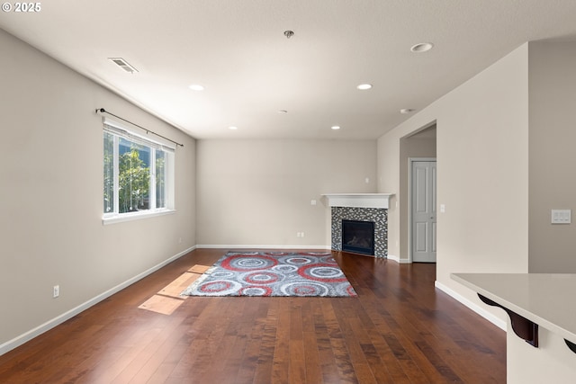 unfurnished living room featuring hardwood / wood-style flooring, recessed lighting, a tiled fireplace, and baseboards