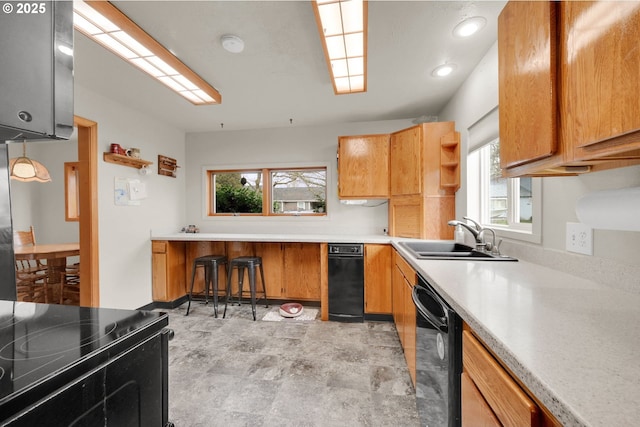 kitchen with black appliances, light countertops, a sink, and brown cabinetry