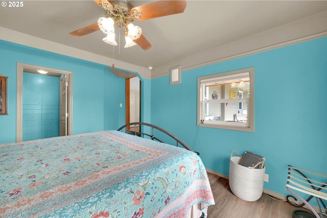 bedroom featuring a ceiling fan, baseboards, and wood finished floors