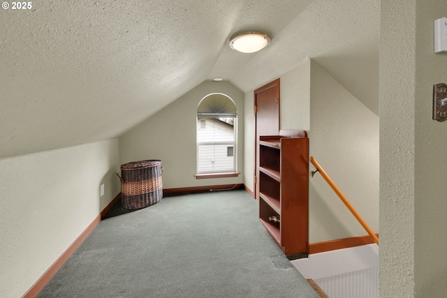 bonus room with a textured wall, light carpet, vaulted ceiling, a textured ceiling, and baseboards