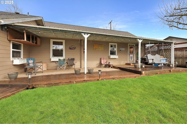 rear view of house featuring a lawn, a deck, and fence