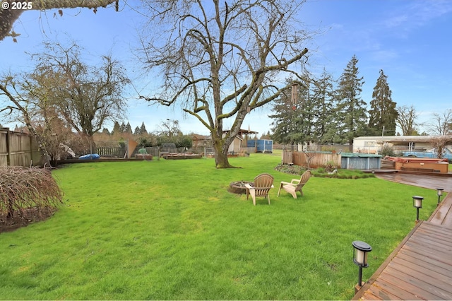 view of yard with a fenced in pool, an outdoor fire pit, a fenced backyard, and a wooden deck