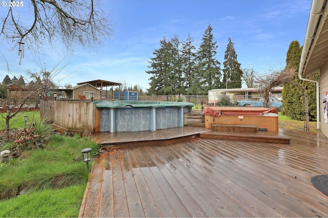 wooden deck with a fenced in pool and a covered hot tub