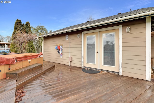 wooden deck with a hot tub and french doors