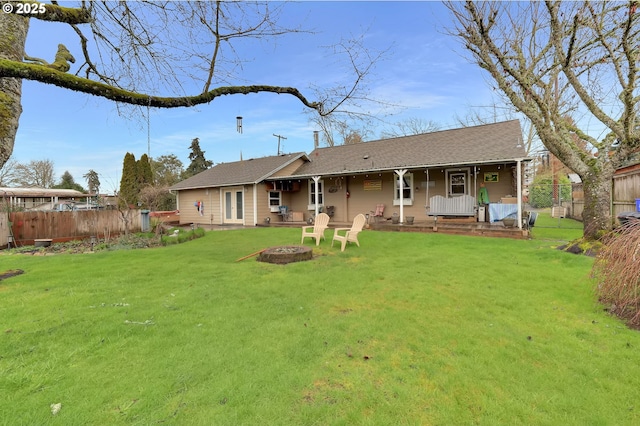 back of property featuring a fire pit, a lawn, covered porch, and fence